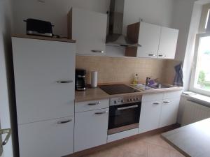 a kitchen with white cabinets and a stove top oven at Apartment Zur Bauhütte, WLAN in Hohenstein-Ernstthal +2 photos