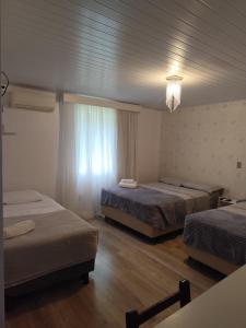 a hotel room with two beds and a window at Recanto Vó Eni in Gramado