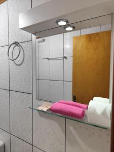 a bathroom with a mirror and pink towels on a shelf at Recanto Vó Eni in Gramado +99 photos