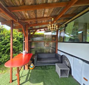 a patio with a couch and a table and a bus at Atomi CountryBus in Aucugals