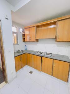 an empty kitchen with wooden cabinets and a sink at Stay lux yellow in Islamabad +7 photos