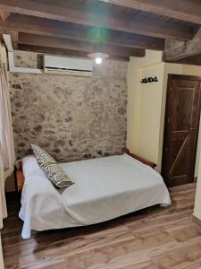 a bedroom with a white bed with a stone wall at Apartamentos EL Wala in Hervás