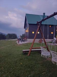 a swing set in a field in front of a building at Vila Danida in Žabljak