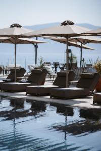 a pool with chairs and umbrellas next to the water at Magnus Hotel & SPA in Vlorë +31 photos