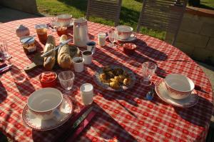 una mesa de picnic con comida en un paño de mesa blanco y rojo en La Ferme de Menoun en Thil