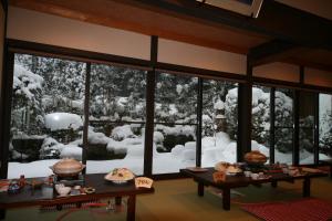 una sala da pranzo con neve fuori da una finestra di Yumoto Onsen OharaSansou a Kyoto