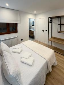 a bedroom with a white bed with two towels on it at Laros Pios Alojamiento 4 in Villalba