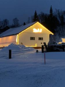 a barn with lights on the side of it in the snow at Hagen Camping Mini hus in Kjerrvika
