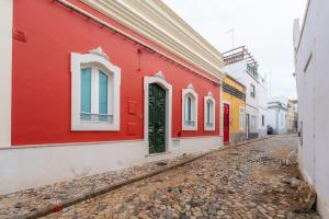 a red building with a green door on a street at Casa Butterfly in Faro +66 photos