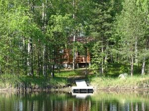 a cabin in the woods with a boat in the water at Lomasaaret Cottages in Villala