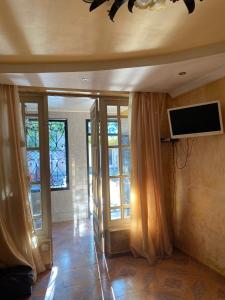 a living room with a tv and some windows at Silk Way in Ureki