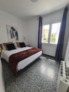 a bedroom with a large bed and two windows at Apartament Santa Margarida in Roses