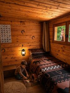 a boy playing with a bed in a log cabin at Les Ecuries du Ranch in Les Cresnays