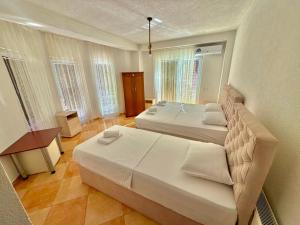 a bedroom with two beds and a table and windows at Vala Rooms in Struga
