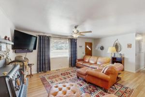 a living room with leather furniture and a flat screen tv at Hummingbird Retreat in South Fork
