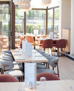 a restaurant with tables and chairs and windows at Hôtel Le Phare in Ouistreham