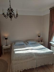 a bedroom with a bed and two tables and a chandelier at Villa Matilda in Uusikaupunki