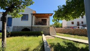 a white house with a porch and a stone wall at House RudNik in Silent Village, Island Krk in Isola Veglia