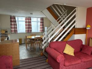 a living room with a red couch and a staircase at Villa 118 Dawlish Warren in Dawlish Warren