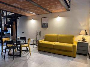 a living room with a yellow couch and a table at Atelier Volturno in La Maddalena
