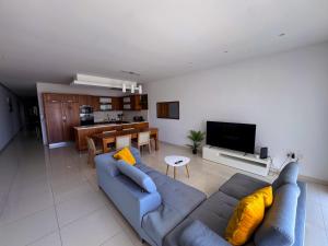 a living room with a blue couch and a kitchen at Marsaxlokk Harbour View Apartment in Marsaxlokk