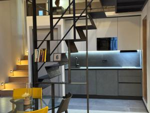 a spiral staircase in a kitchen with yellow chairs at Atelier Volturno in La Maddalena +5 photos
