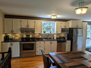 a kitchen with white cabinets and a wooden table with a tableablish at Finnegan's Cottage in Placentia