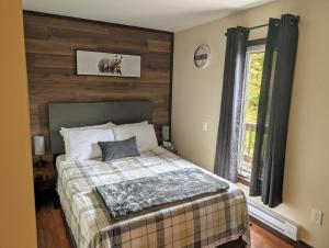 a bedroom with a bed with a wooden wall at Finnegan's Cottage in Placentia