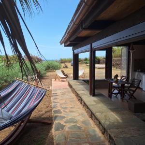 a hammock hanging outside of a house with a patio at Dammuso Surya Il cappero monolocale in Pantelleria