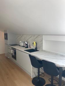 a kitchen with a counter and two blue chairs at Appartement Wonder 2 au centre de Couvet in Couvet +12 photos