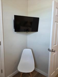 a white chair sitting under a flat screen tv on a wall at Shore Getaway 2 in Atlantic City
