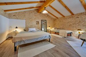 a bedroom with two beds and a brick wall at Small stone house in Ližnjan +19 photos
