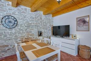 a dining room with a table and a tv and a stone wall at Small stone house in Ližnjan