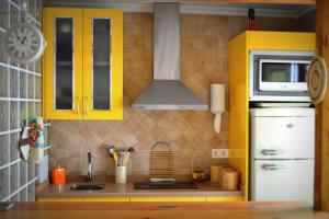 a small kitchen with yellow cabinets and a white refrigerator at La Bolsa Apartment in Málaga