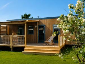 a wooden cabin with a chair on a deck at Domaine MON CALME in Piriac-sur-Mer