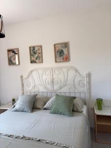 a white bed with four pictures on the wall at Apartmani Primorski kutak in Jadranovo