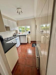 a kitchen with white cabinets and a tile floor at Pegs Cottage in Clonmel