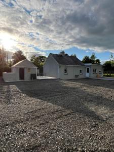 a house on a gravel road in front of a building at Pegs Cottage in Clonmel