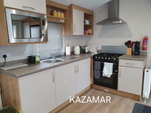 a kitchen with white cabinets and a black stove top oven at Kazamar in East Mersea