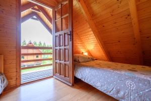 an attic bedroom with a bed and a large window at Domki letniskowe Nevada in Darlowko