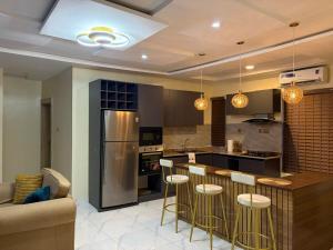 a kitchen with a bar with stools and a couch at Modern 2 BR apartment in Lekki