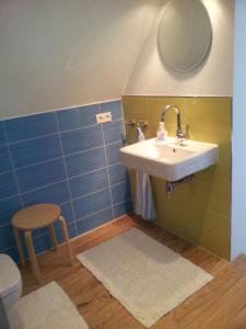 a bathroom with a sink and a stool at Ferienwohnungen Abraham in Nienhagen