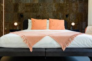 a bed with orange and white sheets and pillows at B&Biotope in Heusden
