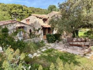 a stone house with a bench and a dog in the yard at La Petite Bergerie in Éze