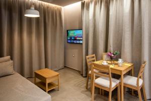 a living room with a table and chairs and a tv at Ivy Residences with Pool in Ayía Varvára
