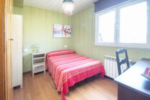 a bedroom with a bed and a table and a window at AG Piso Vazquez Parga Carballo in Carballo +5 photos