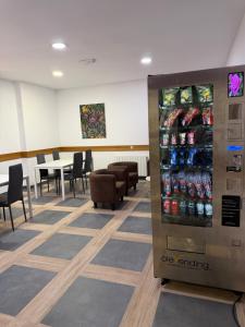 a soda vending machine in a cafeteria with tables and chairs at Pensión La Salve in Bilbao