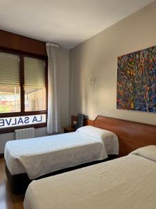 a bedroom with two beds and a painting on the wall at Pensión La Salve in Bilbao +94 photos
