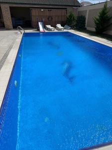 a large blue swimming pool with chairs in a yard at Bilgah Garden Villa in Bilgah