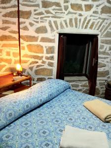 a bed in a room with a stone wall at Medieval Village Rural B&B in Ne